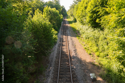 Railway, train tracks going through a forest. Beautiful sunlight and nature. Normandy, France. Bridge in the background. View from up high.