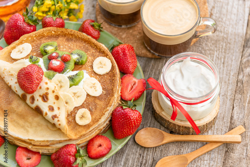 Edible bear with strawberries on pancakes and a jar of sour cream.