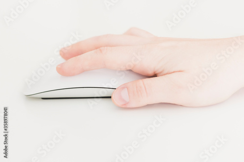 Caucasian female hand, using a white wireless computer mouse, with a nice design, on a white background. Business woman, selective focus, concepts