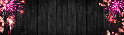 Festive Silvester Party background banner panorama long- Pink firework and bokeh lights on dark black grey wooden wall texture, with space for text