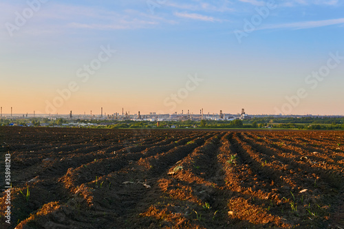 evening rural landscape with a huge oil refinery on the horizon