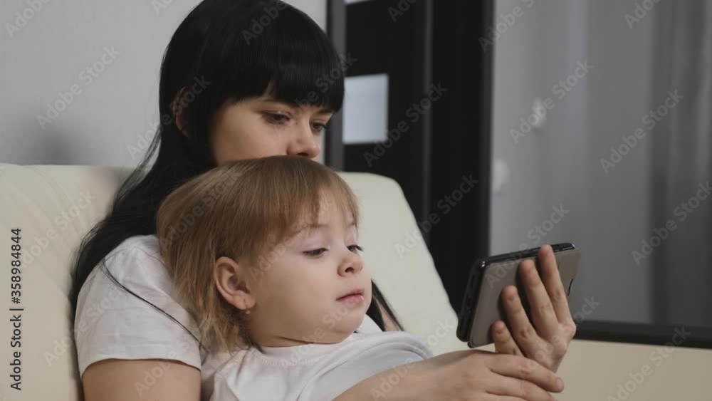 The family sits at home and uses a smartphone to communicate. Mother and daughter in isolation in quarantine. The family sits at home and uses a smartphone to communicate. Mother and daughter in isolation in quarantine.