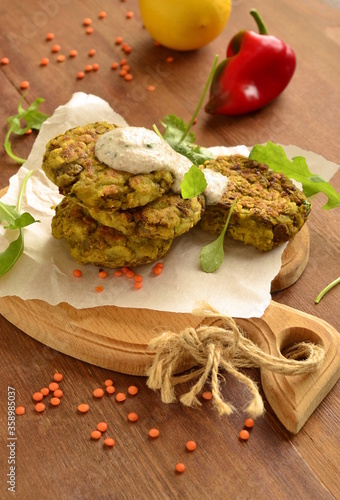 Lentil fritters with zucchini. Served with fresh vegetables and sauce  vertical