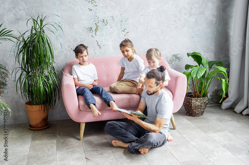 Young father is reading a book to his children. Happy family togetherness and fatherhood. Children spend time with their father. photo