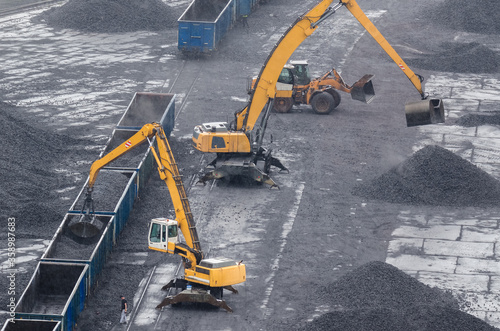 EXCAVATORS AND WHEEL LOADER - Machines at reloading work on a coal yard in rainy weather 