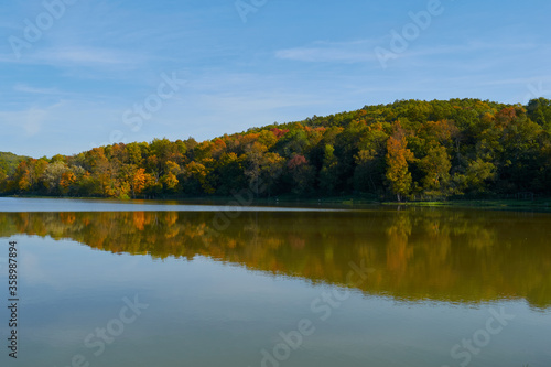 Autumn landscape with colorful trees reflected in the water of the lake