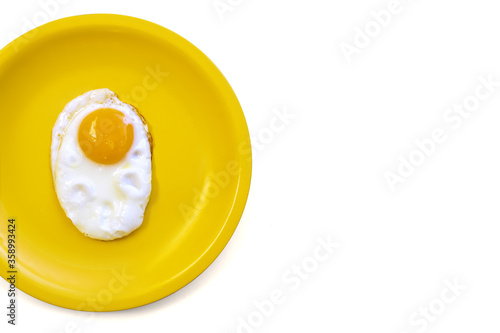 One fried egg with raw yolk on bright yellow plate, isolated on white background. Diet portion concept, food, meal, breakfast. Copy space. Best protein source. Top view.