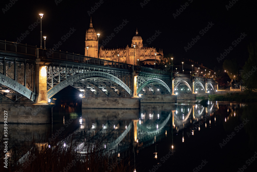 Salamanca Cathedral is a late Gothic and Baroque catedral in Salamanca city. Night wide view of the historic city of Salamanca with New Cathedral and Enrique Esteban bridge. Castile and Leon in Spain.