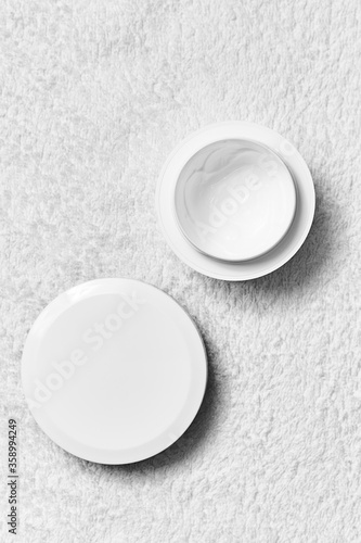 two white jars of cream on a white towel .mocap, flat lay, top view, close up, copy space