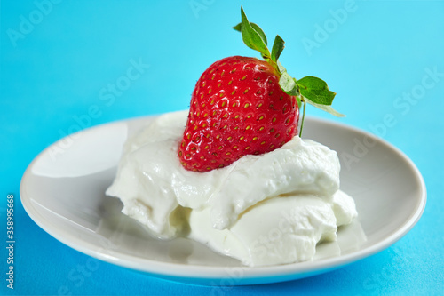 Strawberries and whipped cream on a blue background.