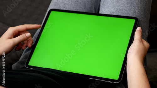 Female relaxes at home with big green screen display tablet 4K footage
