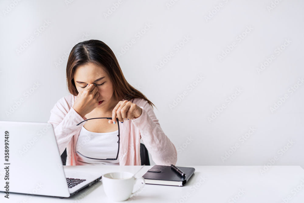 Tired and stressed young asian woman feel pain eyestrain and rubbing her eyes and take off her glasses while sitting at her working place Tired and stressed young asian woman feel pain eyestrain and rubbing her eyes and take off her glasses while sitting at her working place