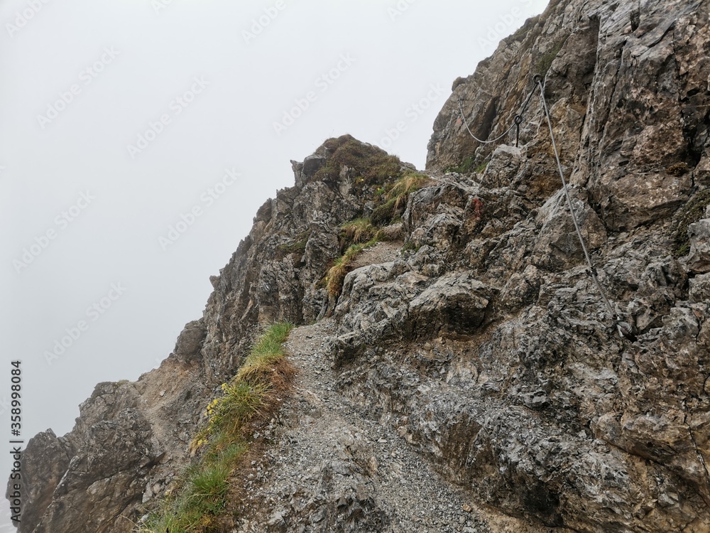 Hiking path between fiderepass hut and mindelheimer hut in the bavarian alps on a wet rainy spring day