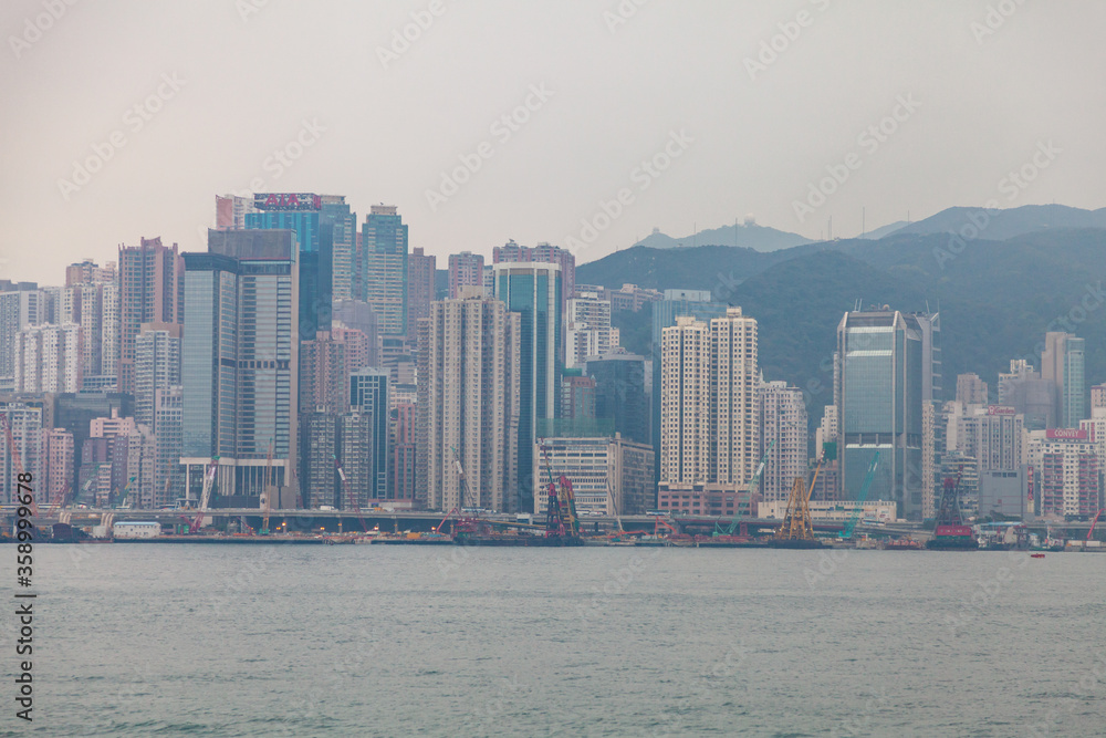 Hong Kong, February 2014: waterfront on Hong Kong island in megalopolis. Tourist destination of large Asian city with sights and views. Urban landscape of embankment in fog.