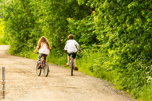 Two children ride nearby on bicycles in the park on a summer sunny day.
