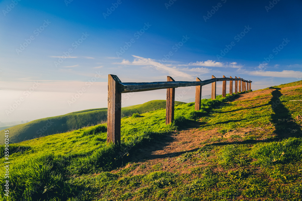 Observation point with wooden fence in green hills at sunset