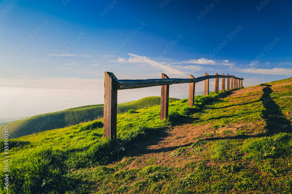Observation point with wooden fence in green hills at sunset Observation point with wooden fence in green hills at sunset