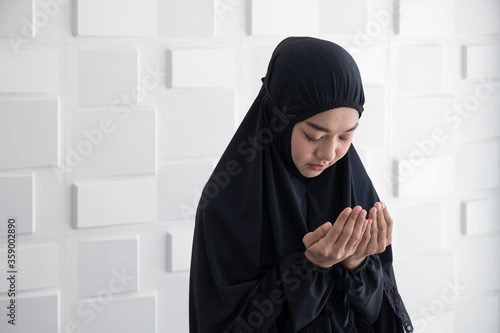 Asian young Muslim woman praying.