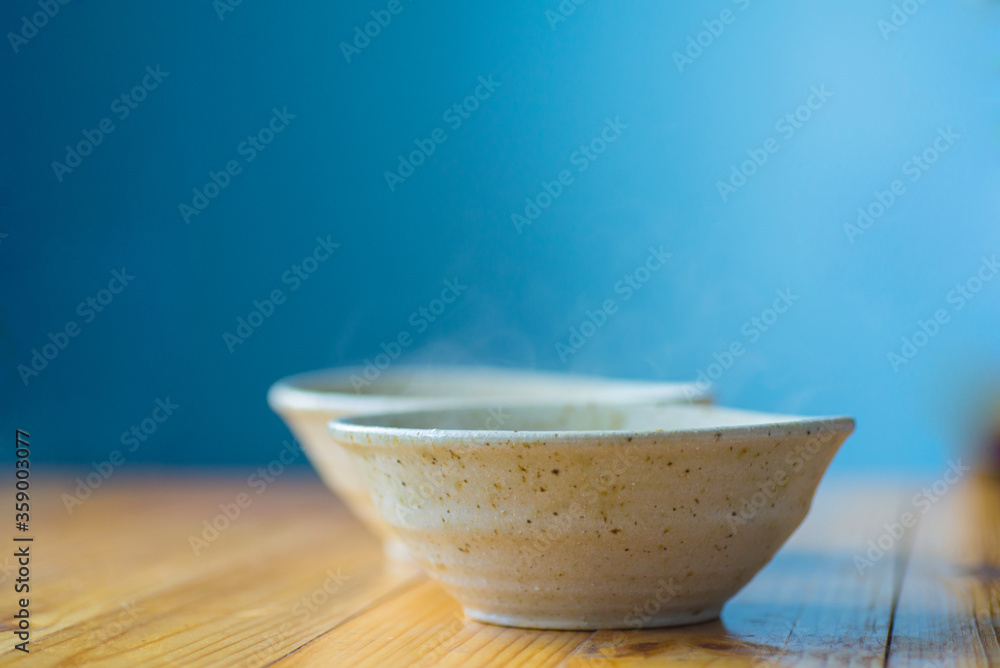 Two ceramic bowls with a hot dish on a wooden table on a blurred background. Two ceramic bowls with a hot dish on a wooden table on a blurred background.