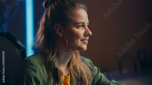 Stylish, Beautiful Female Audio Engineer Working in Music Recording Studio, Uses Mixing Board Create Song. Portrait of a Smiling Girl Artist Musician Working at Control Desk