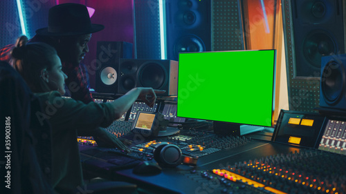 Producer and Audio Engineer Working together in Music Record Studio on a New Album, Use Green Screen Computer, Control Desk for Mixing and Creating Hit Song. Artist and Musician Collaboration