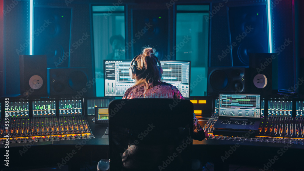 Artist, Musician, Audio Engineer, Producer in Music Record Studio, Uses Control Desk with Computer Screen showing Software UI with Song Playing. Dances. Back View - obrazy, fototapety, plakaty 