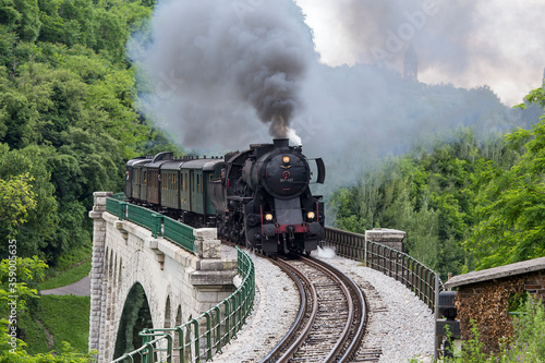 Old steam train crossing the Solkan bridge in Nova Gorica, Slovenia, Europe. Lots of black and gray steam hiding the locomotive, full frame.
