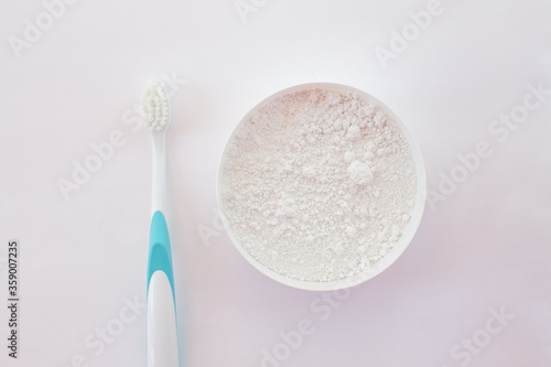 Close-up white tooth powder in an open jar and toothbrush with blue pen on white background. Home Whitening and Hygiene