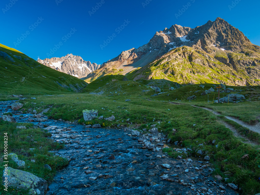 Alpine stream in idyllic valley amid rocks and green meadows, Natural reservoir of fresh water at high altitude on the mountains.