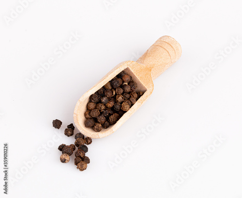 black pepper peas in a wooden spoon and scattered isolated on a white background