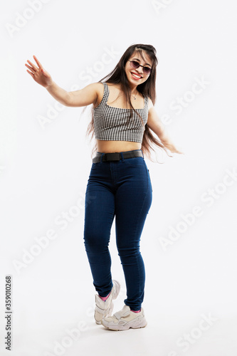 Smiling dancing Young girl in jeans enjoys life. Joy and happiness. Full height. White background. Vertical.