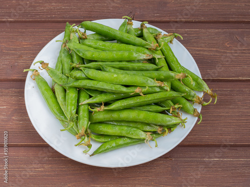 ripe juicy green peas in a plate on a wooden table
