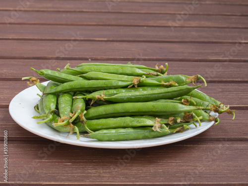 ripe juicy green peas in a plate on a wooden table
