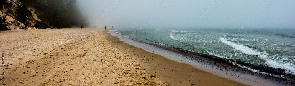 People disappearing in the fog on the beach