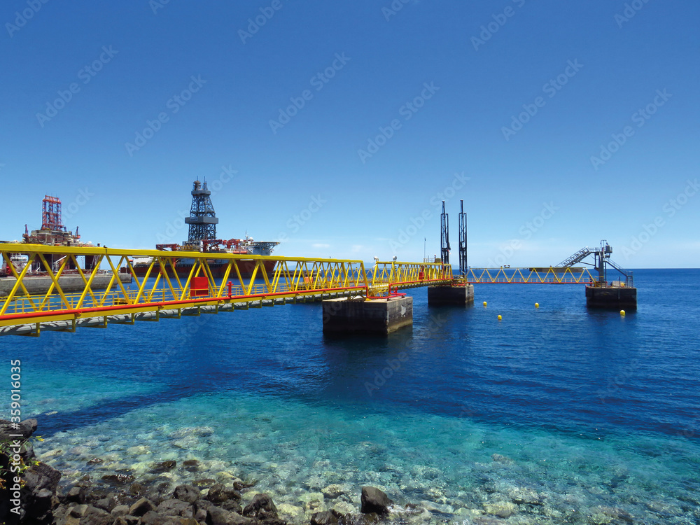Industrial footbridge over crystalline waters, oil platform in maintenance and OFFSHORE oil activities. Maritime and industrial background.