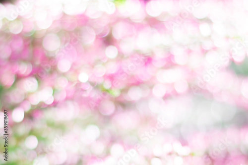 Blurred botanical background with pink, green, yellow sparkles and bokeh effect. Copy space with blurred shining waterdrops, natural background