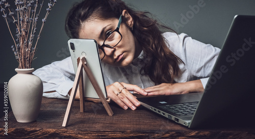 The girl in glasses works from home at the computer and conducts an online broadcast.