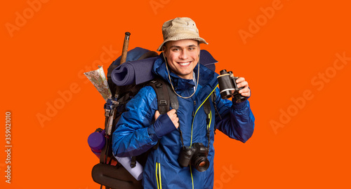 Hiker with binoculars smiling over orange background
