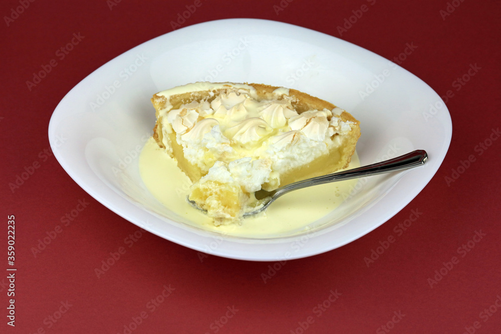A spoonful of lemon meringue pie and cream served in a white dessert bowl. A spoonful of lemon meringue pie and cream served in a white dessert bowl.