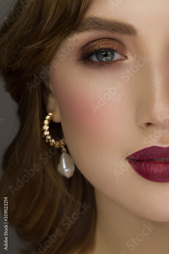 Half a beauty portrait with beautiful fashionable evening make-up, black jiggles on eyes and extremely long eyelashes. Natural lipstick on the lips and blue eyehadow. Cosmetology and facial skin care