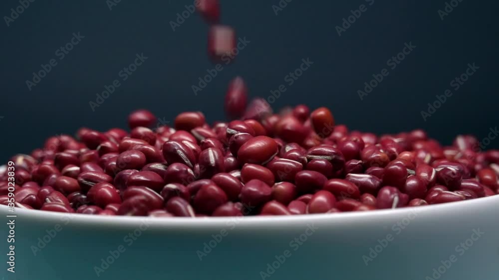 Extreme closeup of red beans poured into bowl, black background, healthy food Extreme closeup of red beans poured into bowl, black background, healthy food