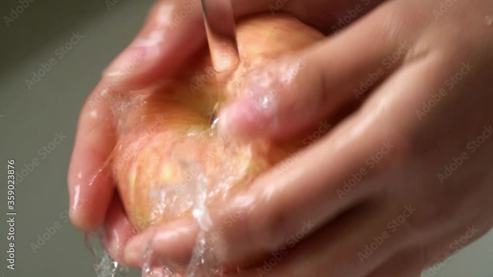 Extreme closeup of hands washing red ripe apple in kitchen, healthy organic food Extreme closeup of hands washing red ripe apple in kitchen, healthy organic food