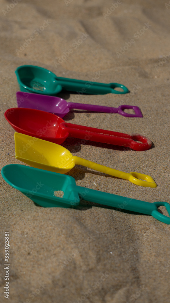 colorful plastic shovels on the beach colorful plastic shovels on the beach