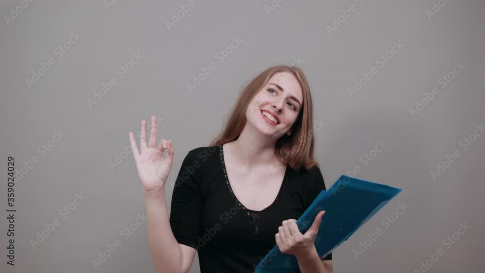 View of hand fingers showing ok sign, gesturing making okay, human emotions, facial expressions, feelings. Young attractive woman, dressed black t-shirt, grey background