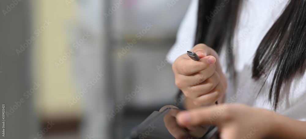 A woman's hands are charging a smartphone while sitting at the black leather sofa. A woman's hands are charging a smartphone while sitting at the black leather sofa.