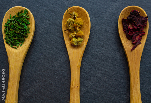 Spices background on wooden spoons. Parsley, chamomile, hibiscus