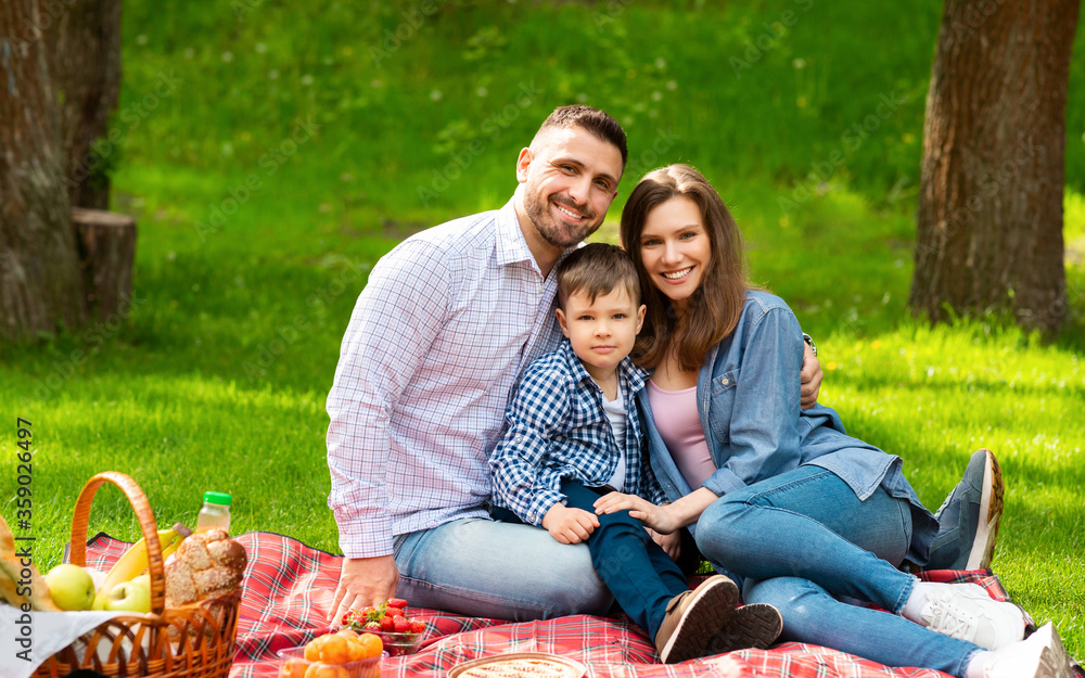 Adorable boy with his parents enjoying sunny summer day on picnic in countryside Adorable boy with his parents enjoying sunny summer day on picnic in countryside