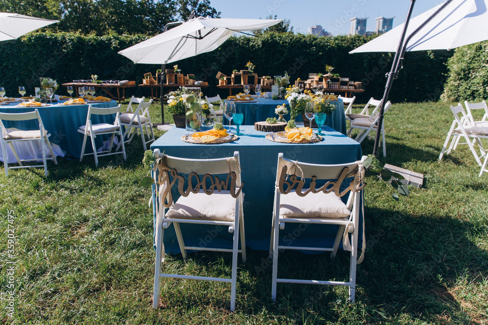 Banquet table setting and decoration. Cutlery on the table. Blue interior decoration. Tables at the outdoors.
