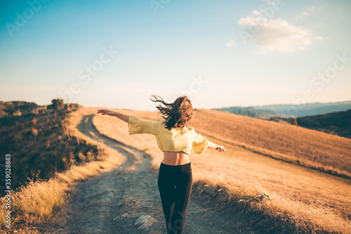 Ragazza felice si diverte in una strada di campagna con maglia gialla e pantaloni neri. photo