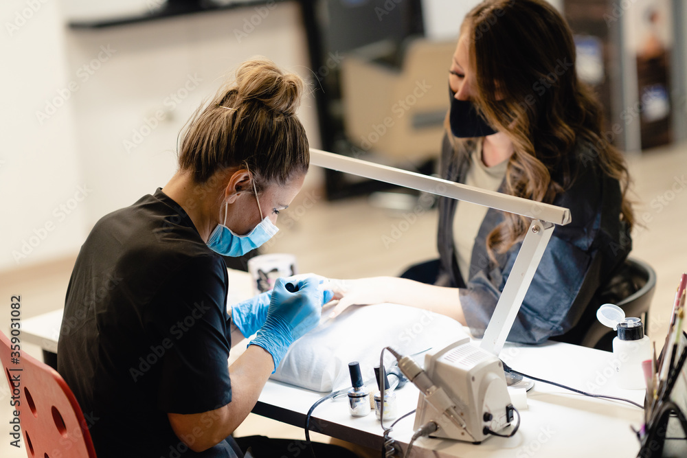 Manicurist paints nails with gel polish on clients nails. Manicurist paints nails with gel polish on clients nails.